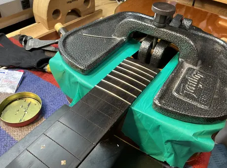 フレットを打ち込む治具をかけたギターのネック